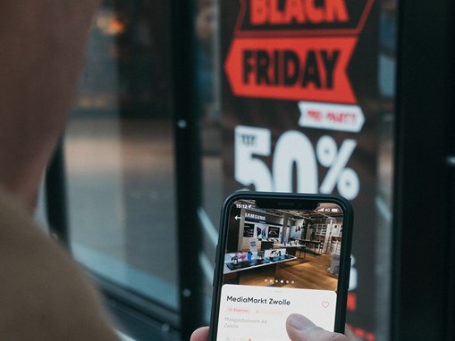 person looking at phone outside a shop door.